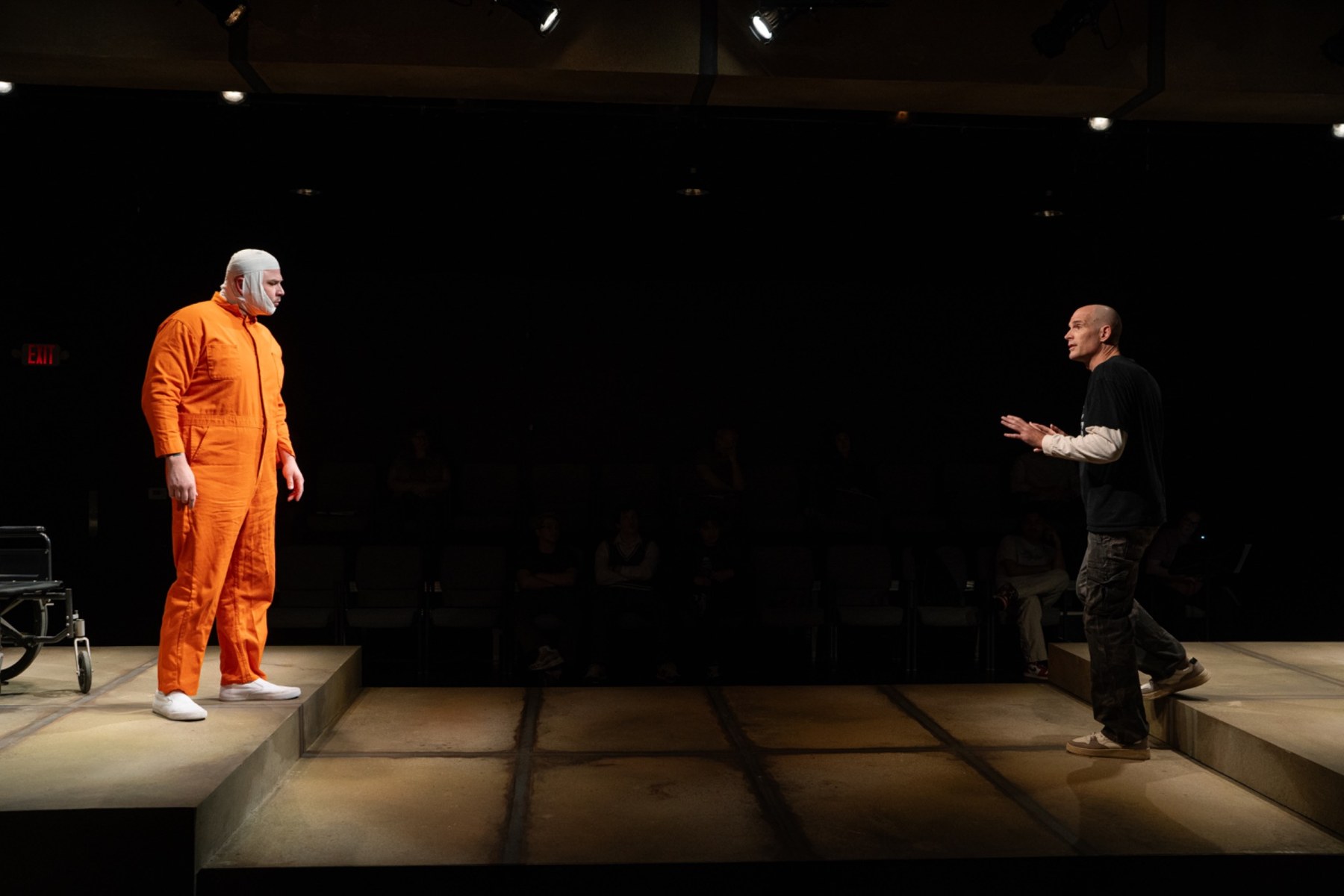 Two actors performing on opposing platforms in a theatre production